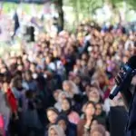 a woman speaking into a microphone in front of a crowd