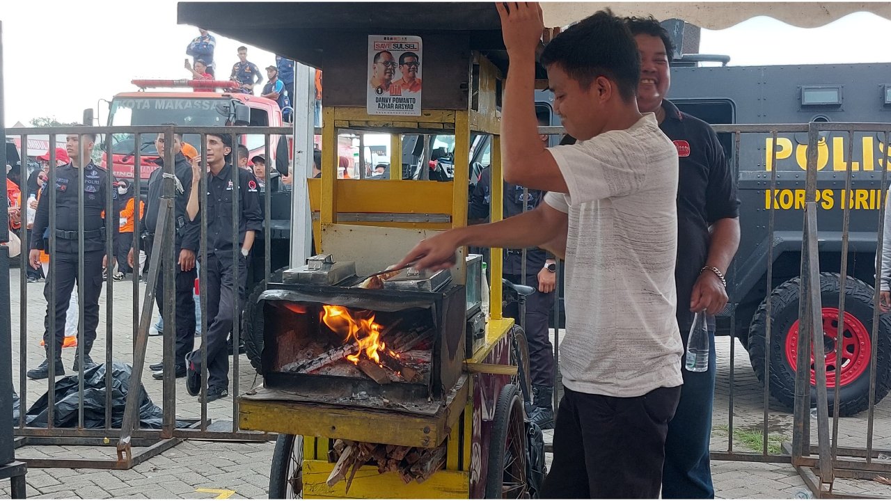 a group of people standing around a small yellow cart with a fire